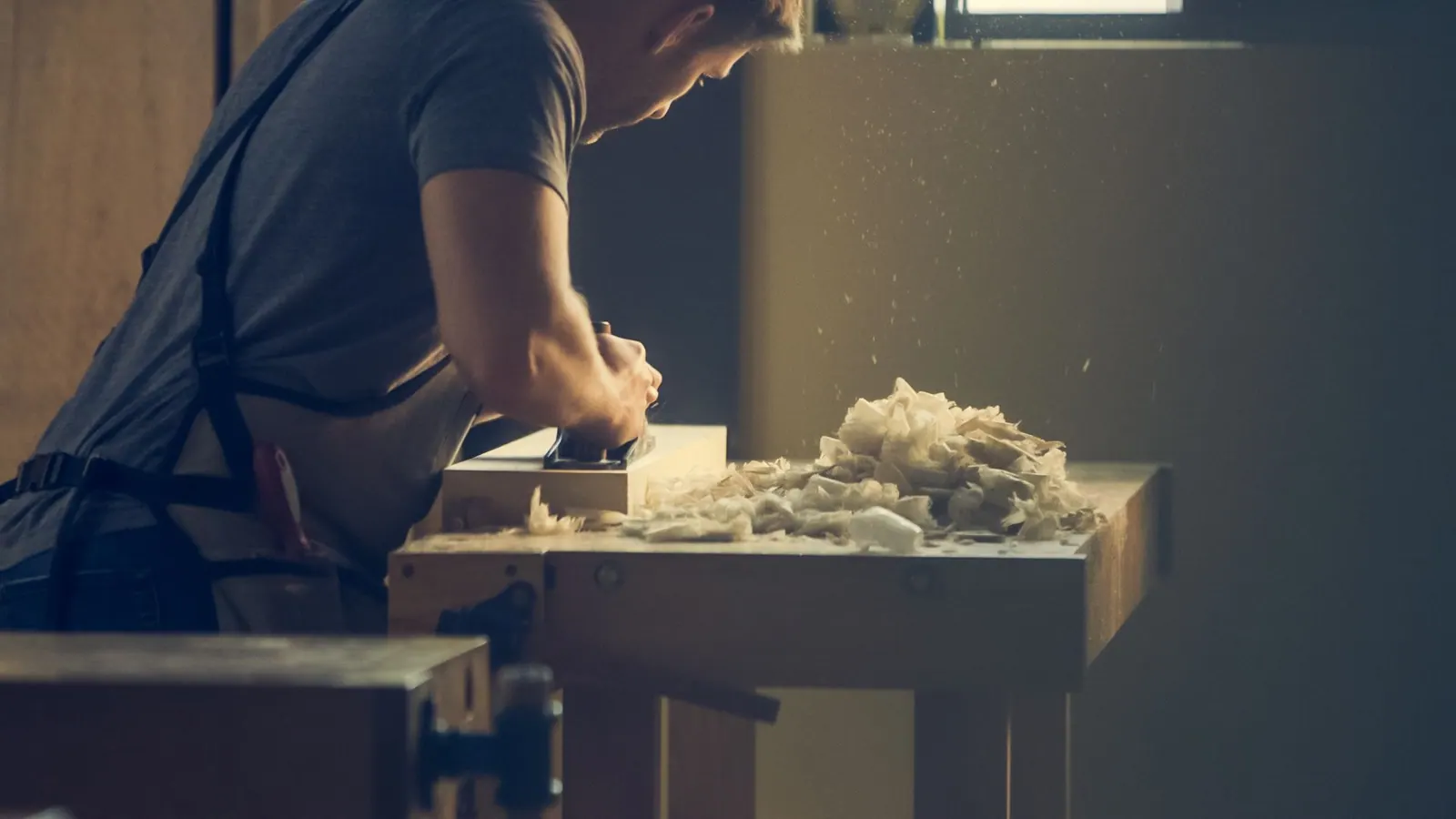 Manos cepillando una tabla de madera maciza con un cepillo de banco